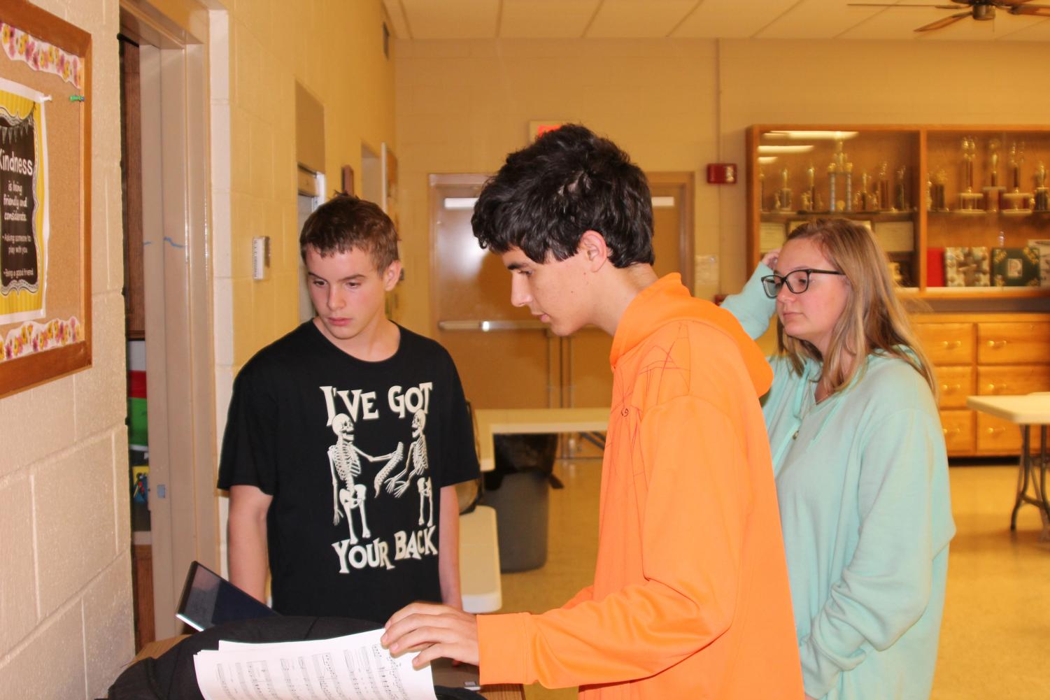 At an afternoon practice at the Catholic church, sophomore Dakota Beck, junior Neal Zoglmann and Paige Lange decide on music for Christmas.