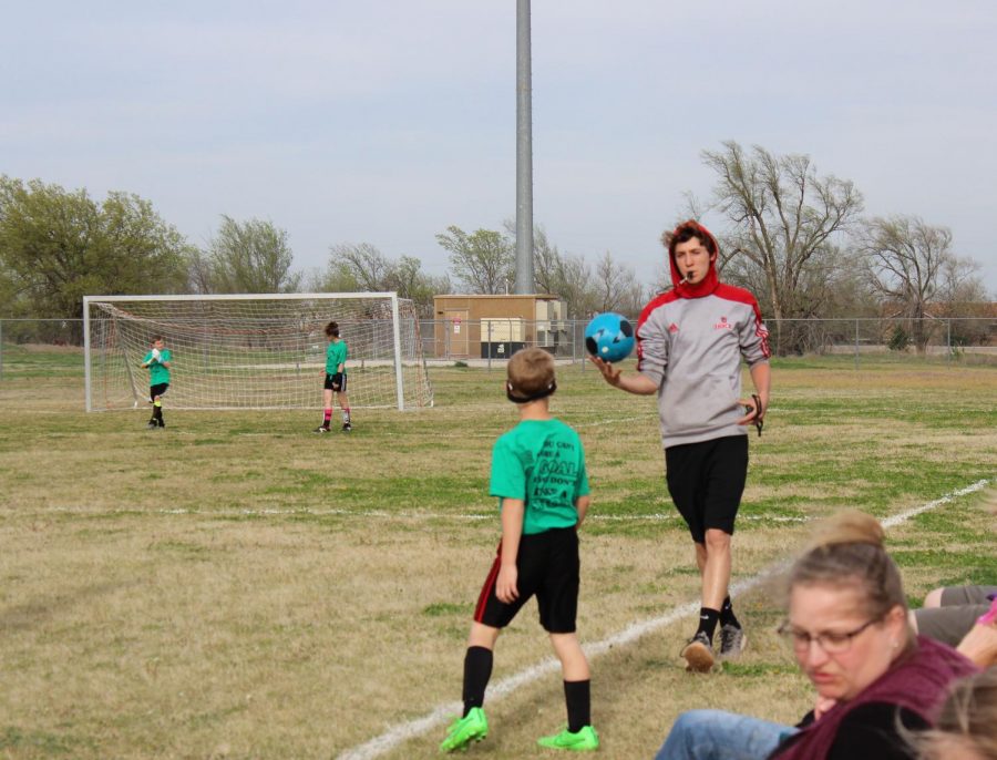 During a soccer game, Carter Bartonek hands the ball to a player to throw in bounds. This was the third day of games for the soccer season, and Bartonek had reffed six games by now.