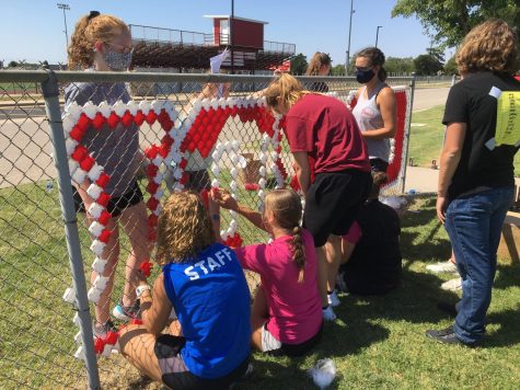 Stuco members place colored fence cups inside the holes of the fence to form the words “CARDINAL PRIDE.” This took place Aug. 22, before school started as an orientation activity. 