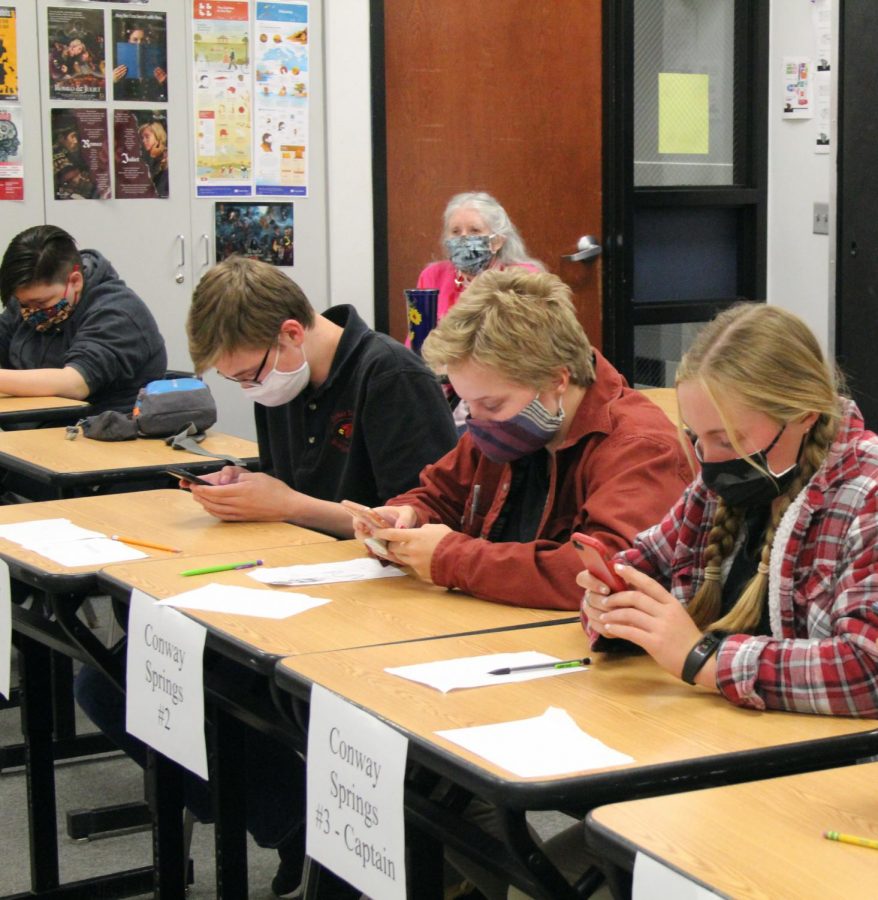During the first virtual meet for Scholars Bowl, seniors Lucy Boyles and Sadie Schmanke and freshman Riley Johnson use their phones to answer questions. “I don’t have a phone so Mrs. Martin let me use hers. It was weird at first and other teams struggled, but then it was fun,” Schmanke said. 

