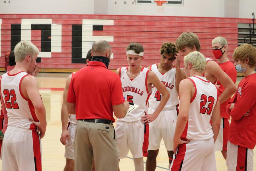 In the heat of the game, the varsity boys basketball team meet with head coach Paul Lange during a timeout to discuss their next play.