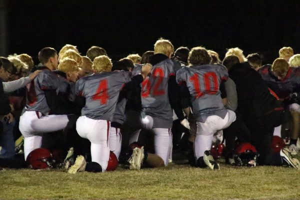 The football team kneels center field after winning their first playoff game against Stanton County Oct. 27. The final score was 56-8. 