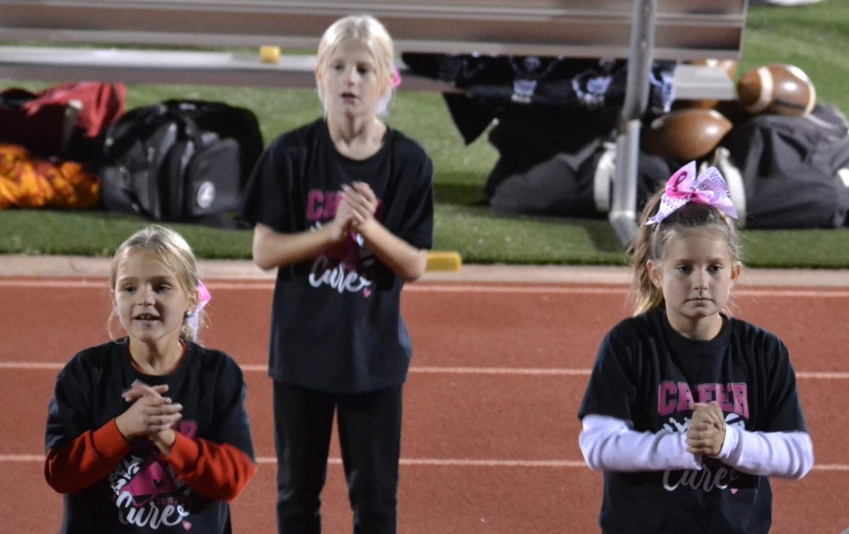 Third graders Kinsley Hemberger, Makayla Carl, Aaralyn Lange help cheerleaders shout loud at a football game. The cheer clinic was held on Oct. 6. Photo contributed by Robyn Lange.
