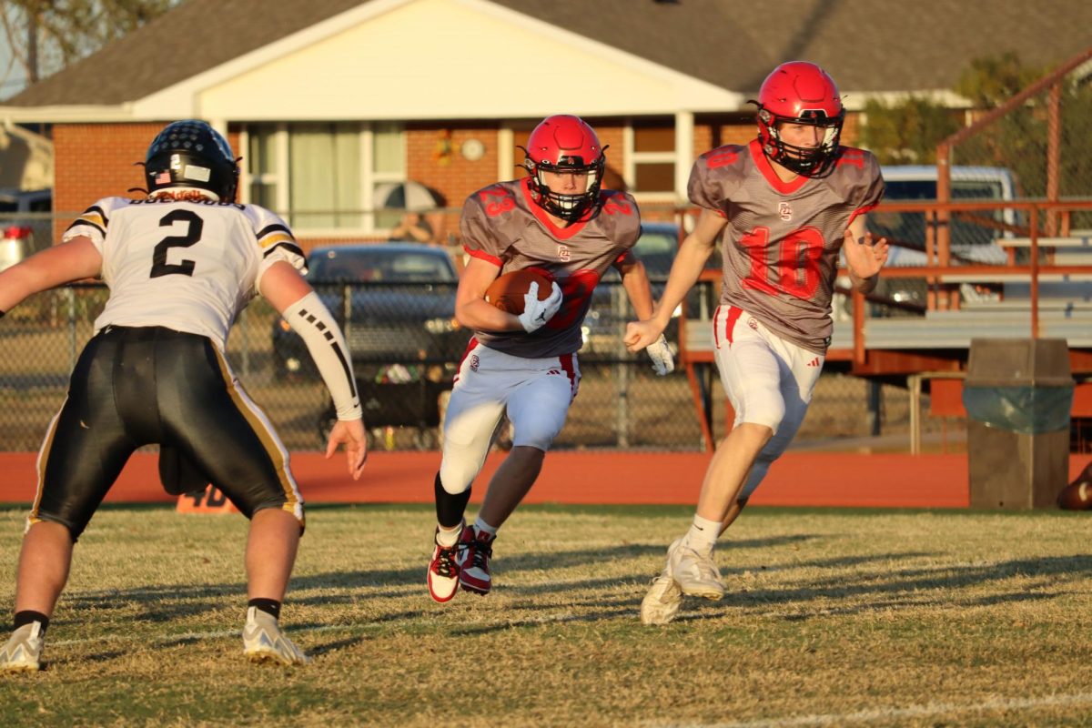 At the Bennington football game senior Grant Fisher carries the ball while junior Logan Osner blocks for him. The Cardinals won this game, against the Bulldogs 59-28.