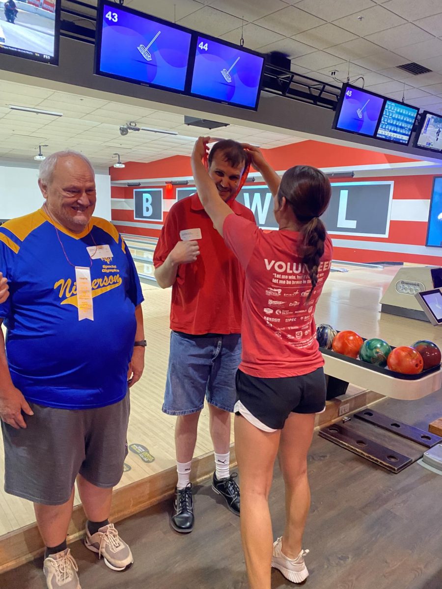 Junior Jaryn Zoglmann awards a participant with a medal. This was at the bowling event. 