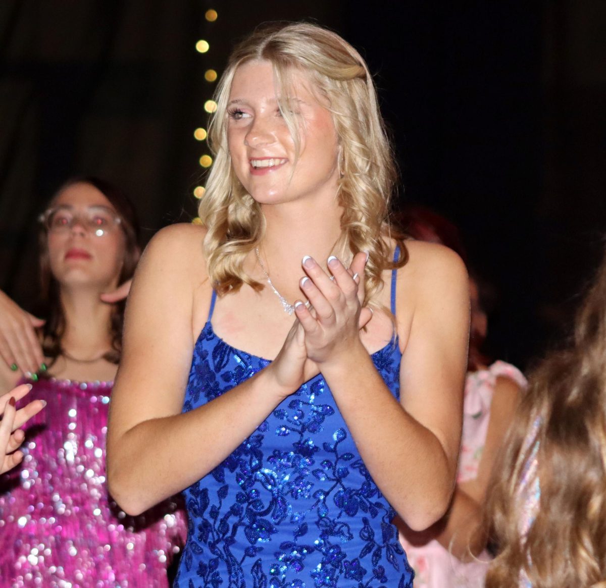 Out on the dance floor, junior Joslin Bartelson claps to a song. Bartelson was smiling at other students that were goofing around.