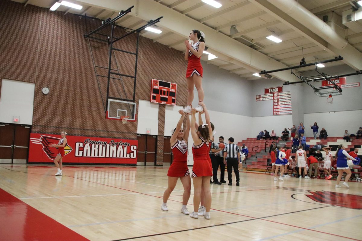 At the basketball game, senior Savannah Reames and juniors Delaney Jones and Brooke Koster were the bases holding up junior Adysen Conkle in a stunt they have been working on. 