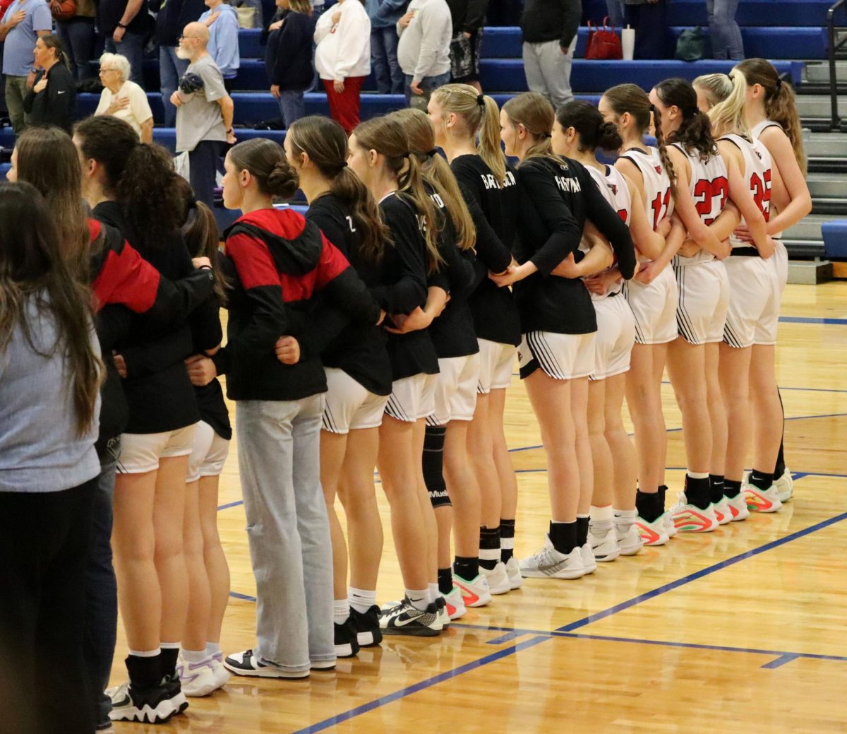 The girls basketball team lines up for the Star Spangled Banner before the game.
